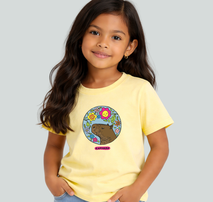Menina usando camiseta infantil amarela com estampa capivara com flores coloridas