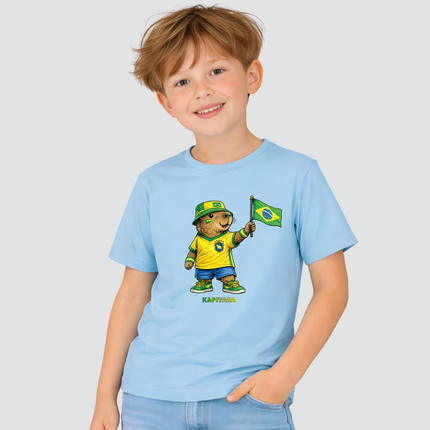 Menino usando camiseta infantil Capivara Torcedora Brasil Copa azul com estampa de capivara segurando bandeira do Brasil