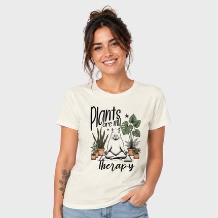 Mulher usando camiseta feminina off white com estampa Plants Are My Therapy de capivara meditando entre plantas